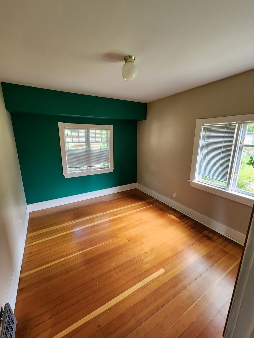 A room with wooden floors and a window with blinds.