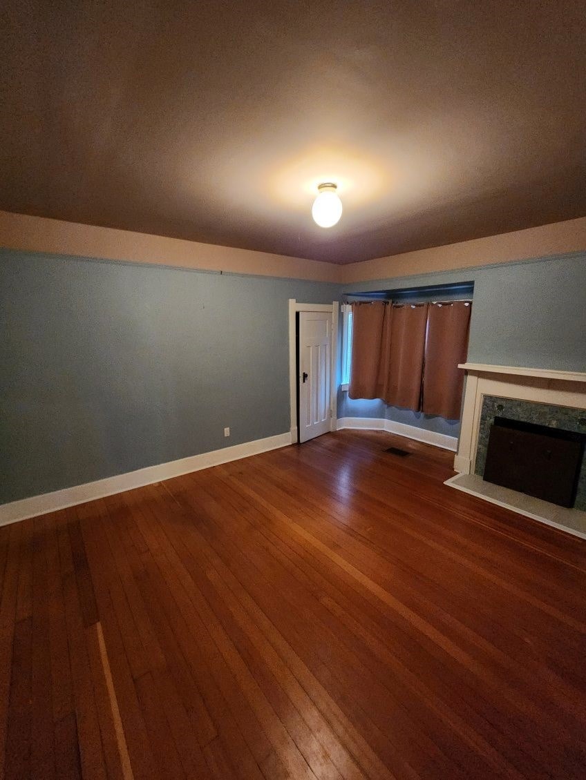 A room with a fireplace and wooden floors.