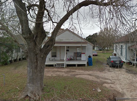 A tree in front of a white house.
