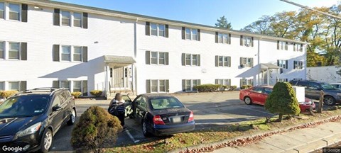 A white building with a black car parked in front.