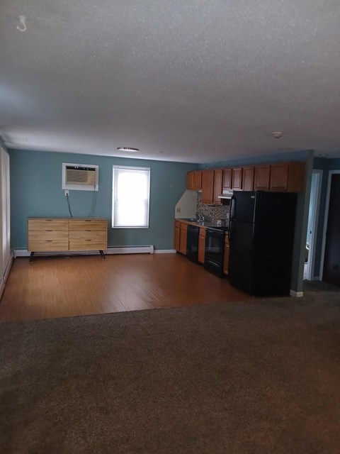 A kitchen with a black refrigerator and wooden cabinets.