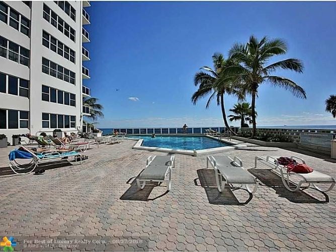 A pool area with lounge chairs and a palm tree.