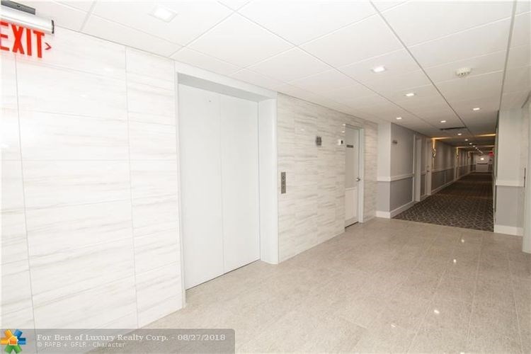 A hallway with a red exit sign above the door.