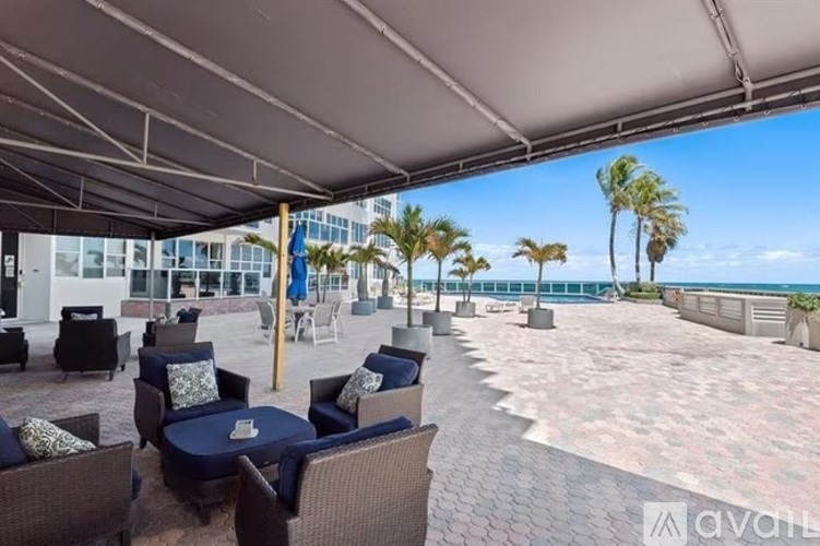 A patio area with chairs and tables under a white canopy.