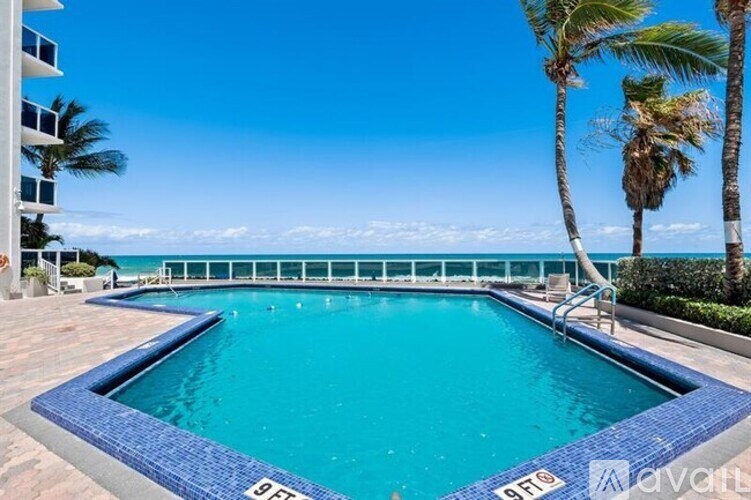 A swimming pool surrounded by palm trees and a clear blue sky.