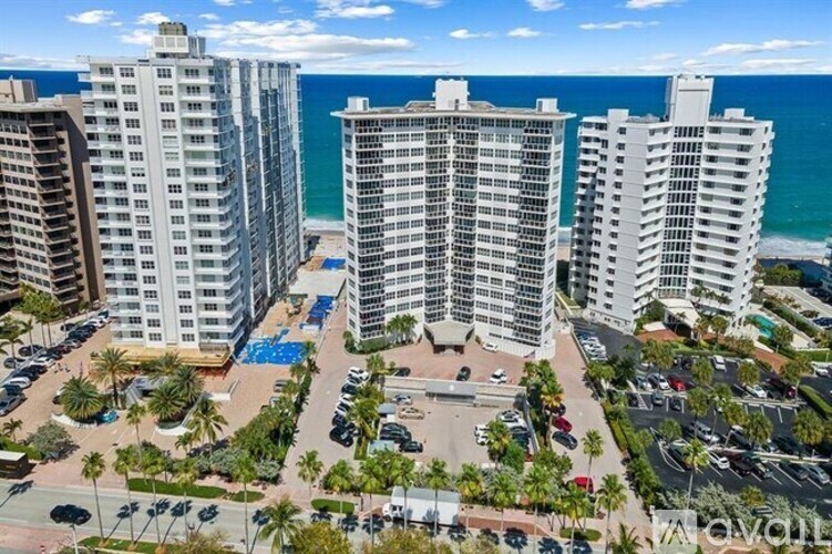 A view of a beachfront condominium complex with a pool and palm trees.