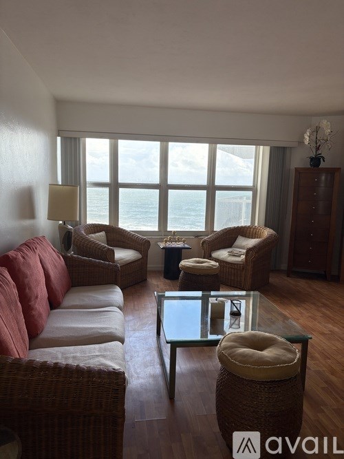 A living room with a large window overlooking the ocean.
