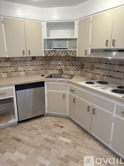 A kitchen with a tiled floor and white cabinets.