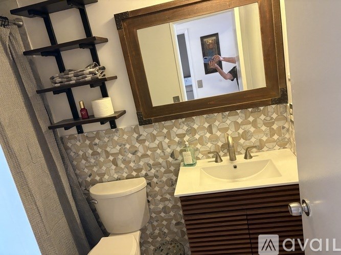 A bathroom with a toilet, sink, and mirror.