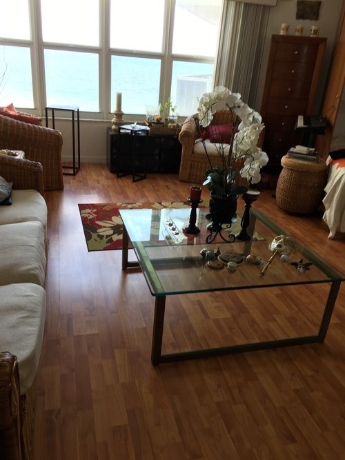 A living room with a glass coffee table and a couch.