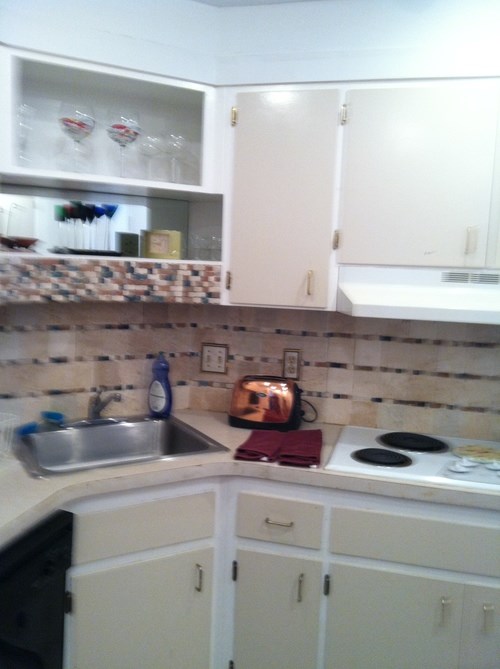 A kitchen with a sink, stove, and cabinets.