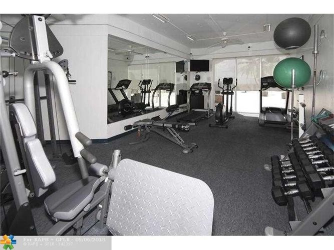 A gym with a variety of equipment including treadmills, weights, and exercise balls.