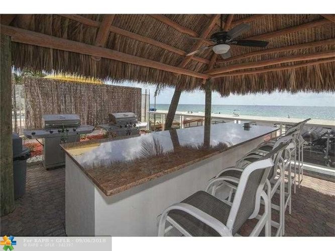 A bar with a thatched roof overlooks the beach.