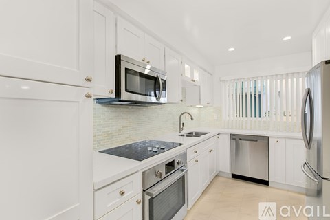 A modern kitchen with white cabinets and stainless steel appliances.