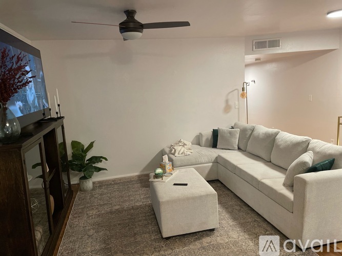 A living room with a white couch, a coffee table, and a television.