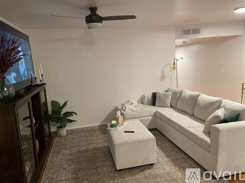 A living room with a white couch, a coffee table, and a television.