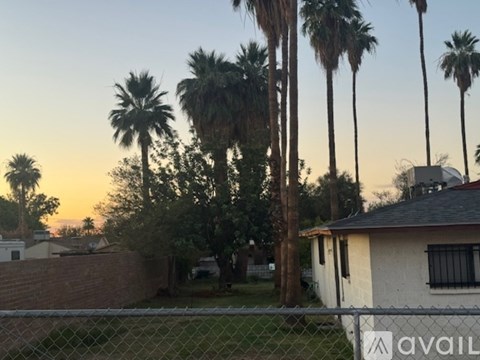 A house with a fence in front of it and palm trees in the background.