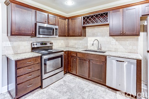 A kitchen with wooden cabinets and a stainless steel dishwasher.