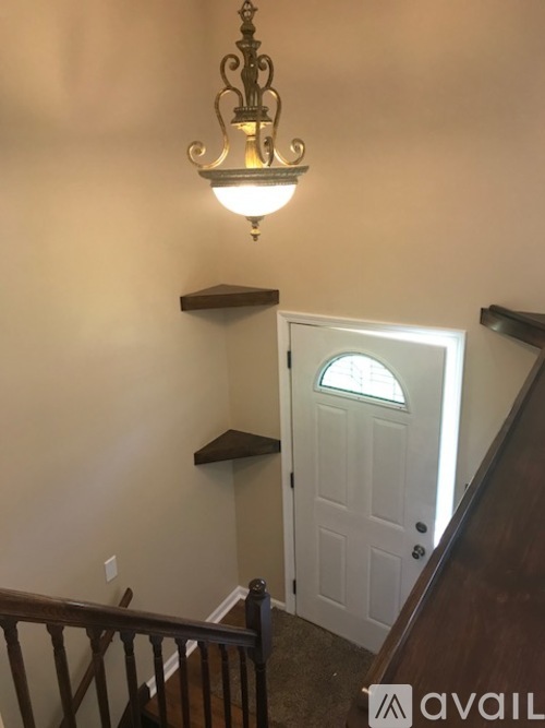 A chandelier hangs over a white door in a hallway.
