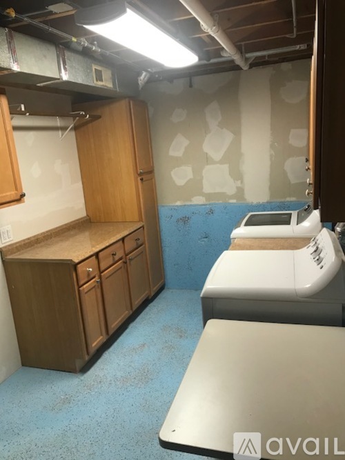 A room with a white sink and wooden cabinets.
