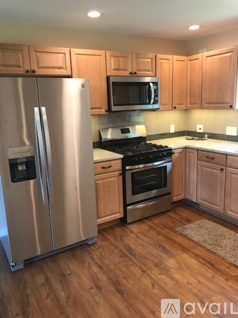 A kitchen with wooden cabinets and a stainless steel refrigerator.