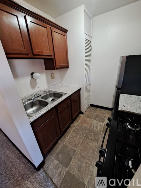 A kitchen with brown cabinets and a black stove top oven.