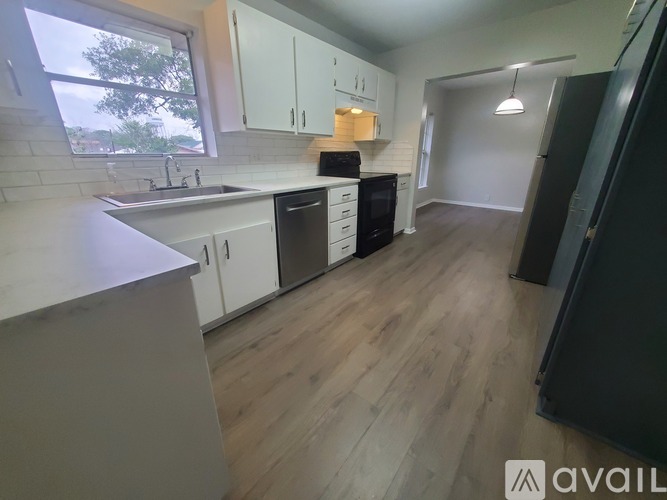 A kitchen with white cabinets and a black refrigerator.