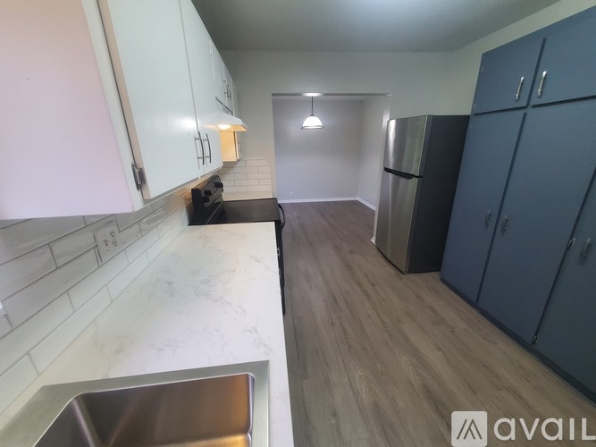 A kitchen with a sink, cabinets, and a refrigerator.