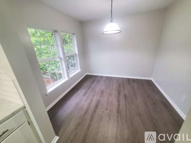 A room with wooden flooring and a window overlooking a garden.