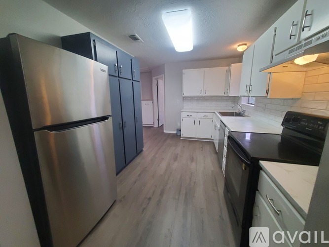A kitchen with a stainless steel refrigerator and wooden floors.