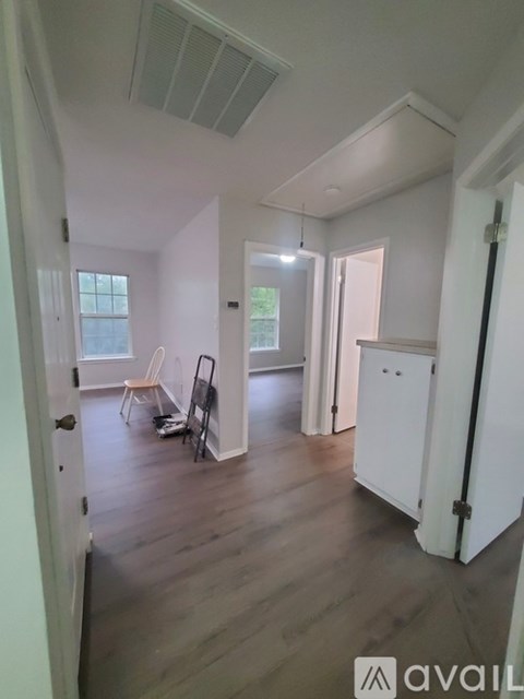 A room with white walls and wooden flooring, furnished with a chair and a table.
