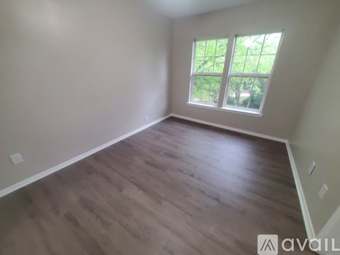 A room with wooden flooring and a window overlooking a green outdoor area.