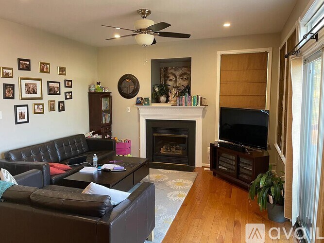 A living room with a fireplace, a couch, a coffee table, a television, and a ceiling fan.
