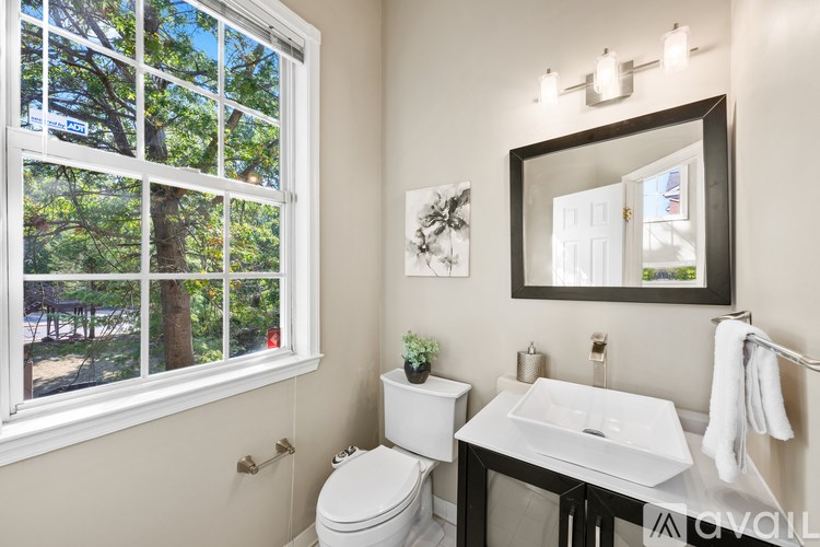 A bathroom with a toilet, sink, and a window.
