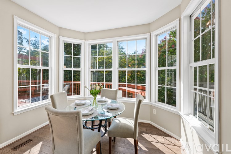 A sunny day in a white room with a round glass table and chairs.