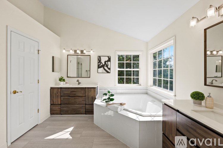 A house with a large bush of pink flowers in front.