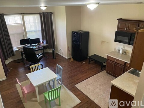 A kitchen area with a table and chairs, a refrigerator, and a microwave.
