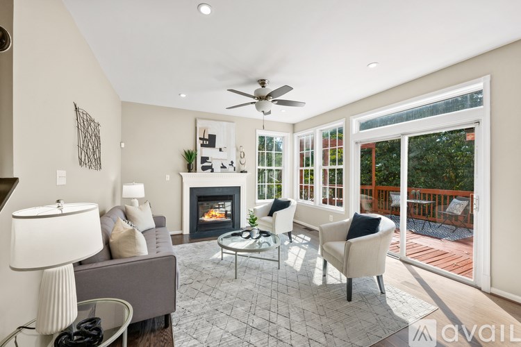 A living room with a grey couch, a fireplace, and a ceiling fan.