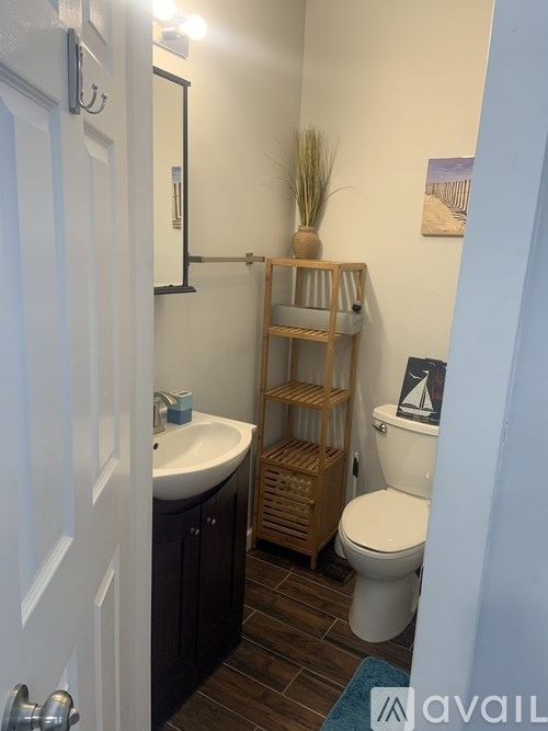 A bathroom with a toilet, sink, and wooden shelf.