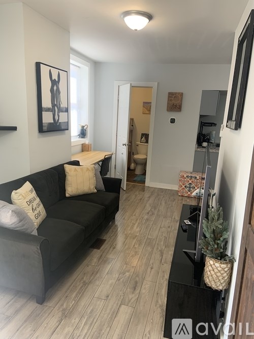A living room with a black couch and a painting on the wall.