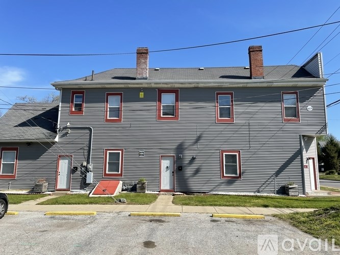 A grey house with red doors and windows.