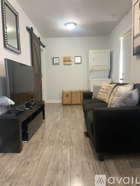 A living room with a black couch and a wooden floor.
