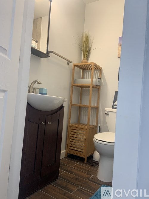 A bathroom with a white sink and a wooden shelf.