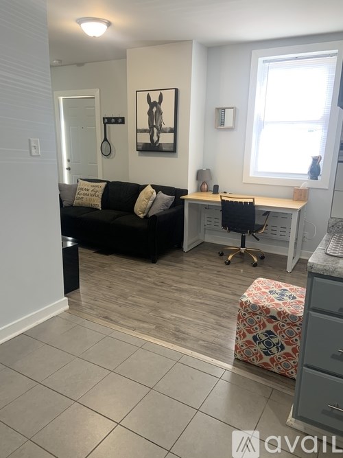 A living room with a black couch and a painting of a horse on the wall.