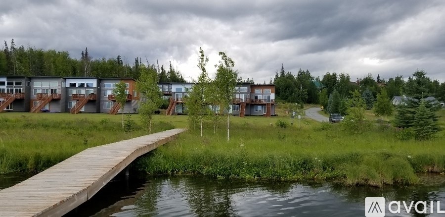 A wooden walkway leads to a row of houses by a body of water.