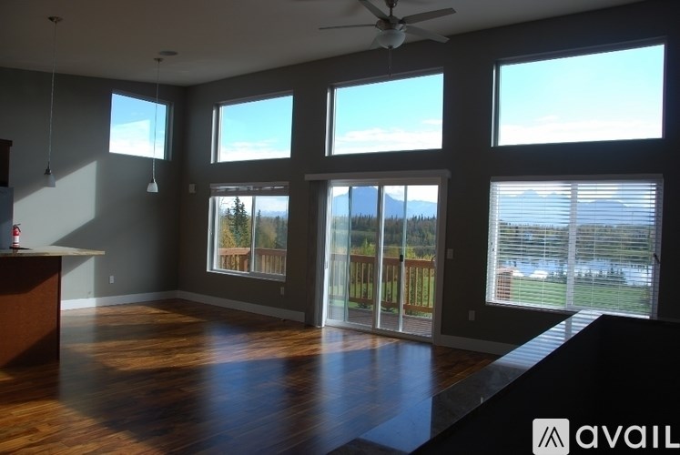 A spacious room with a ceiling fan and large windows overlooking a view.