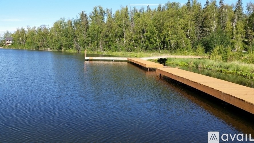 A wooden dock extends into a lake surrounded by trees.