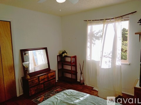 A bedroom with a bed, dresser, and window.