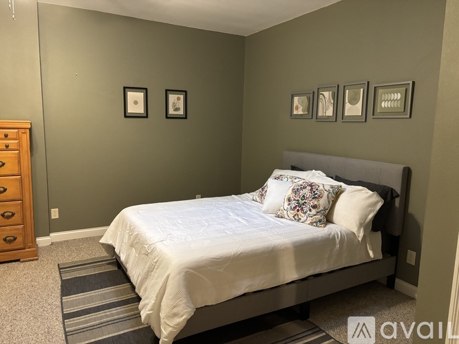 A bedroom with a bed, dresser, and pictures on the wall.
