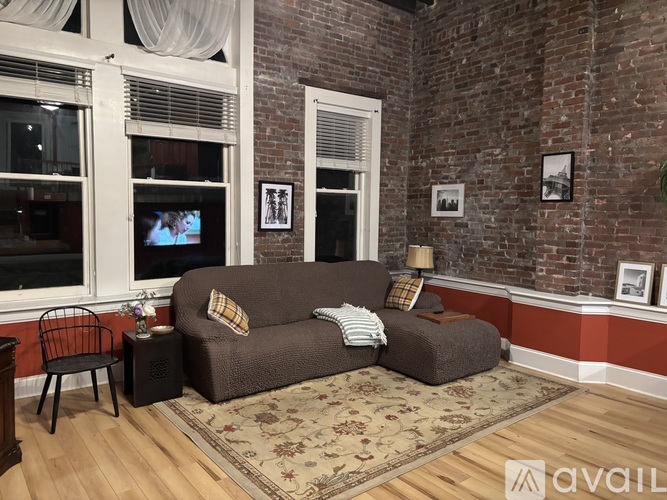A living room with a brown couch and a TV on the window.